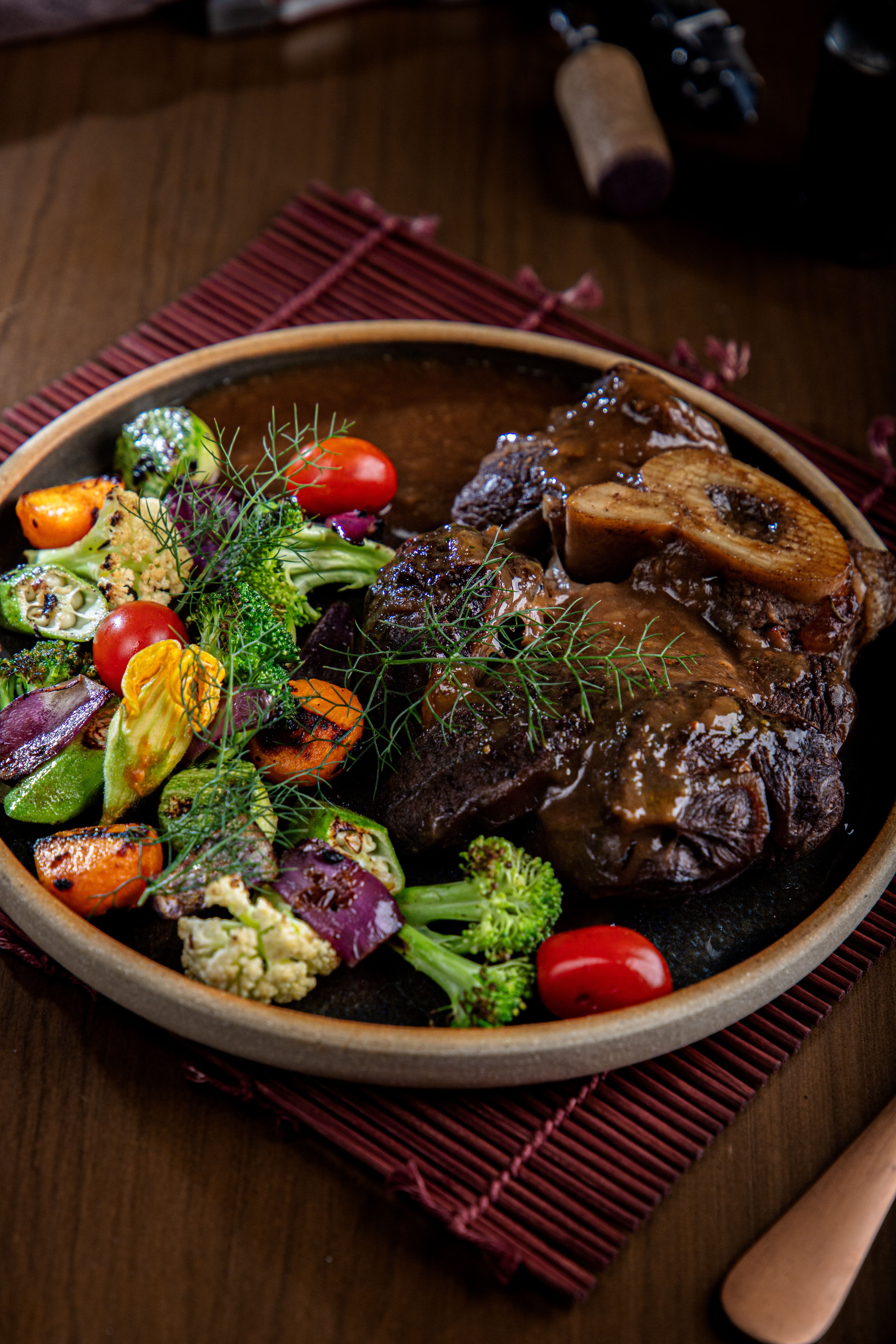 Ossobuco alla milanese in a pan with gremolata, rich braising liquid visible