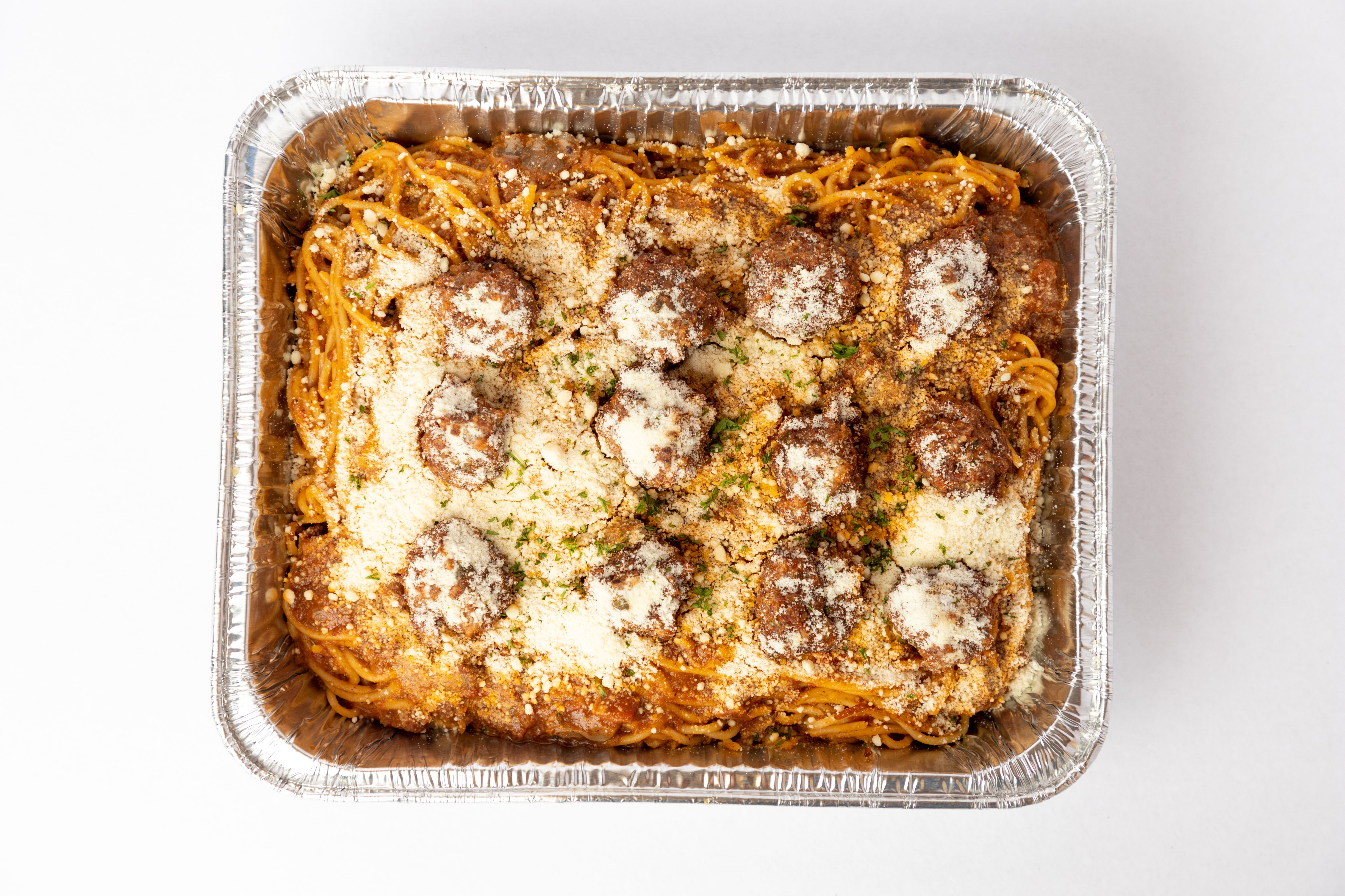 Polpette in tomato sauce in a wide shallow pan with fresh basil